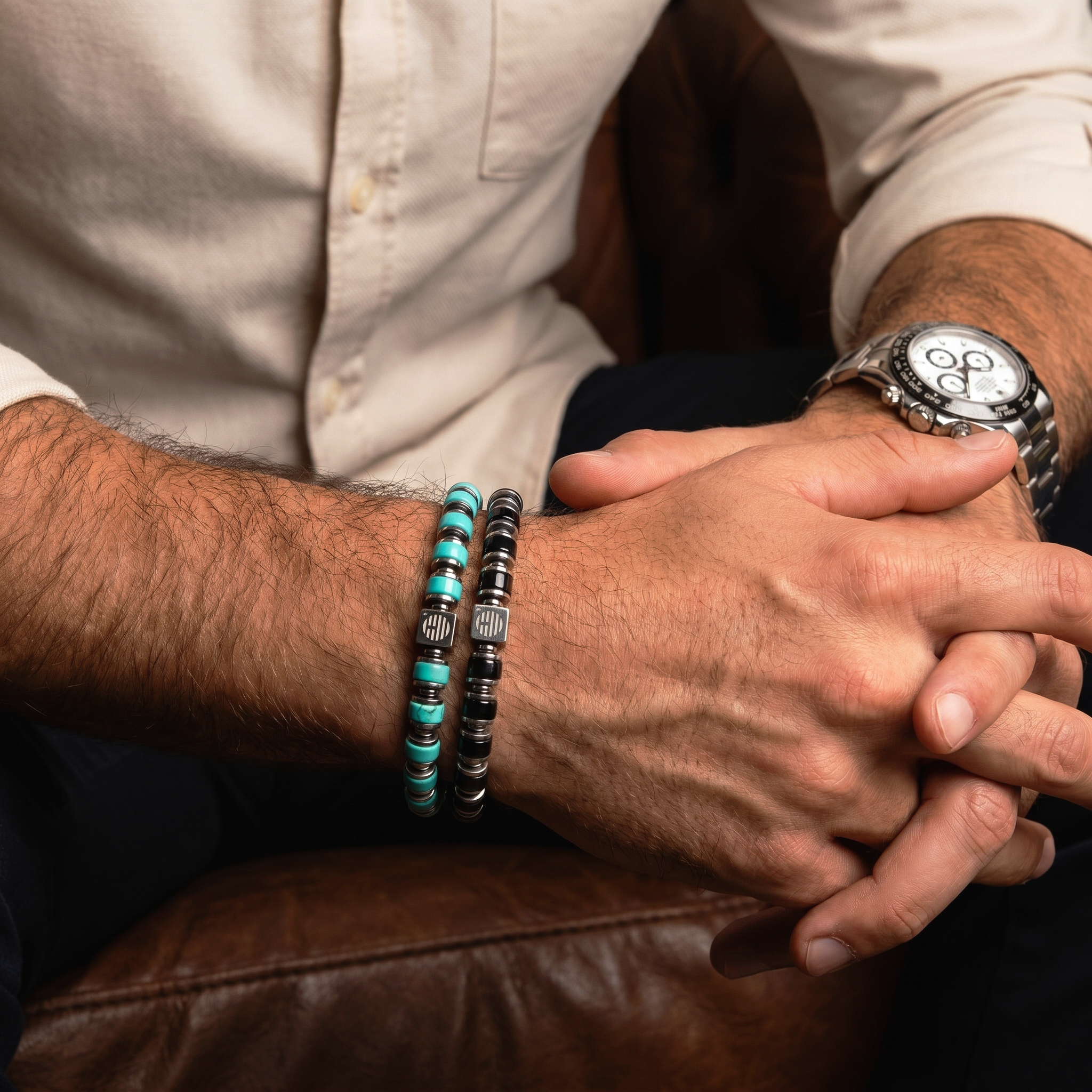 Close-up of a person's wrist with my enchanter bracelets and a watch on a leather surface