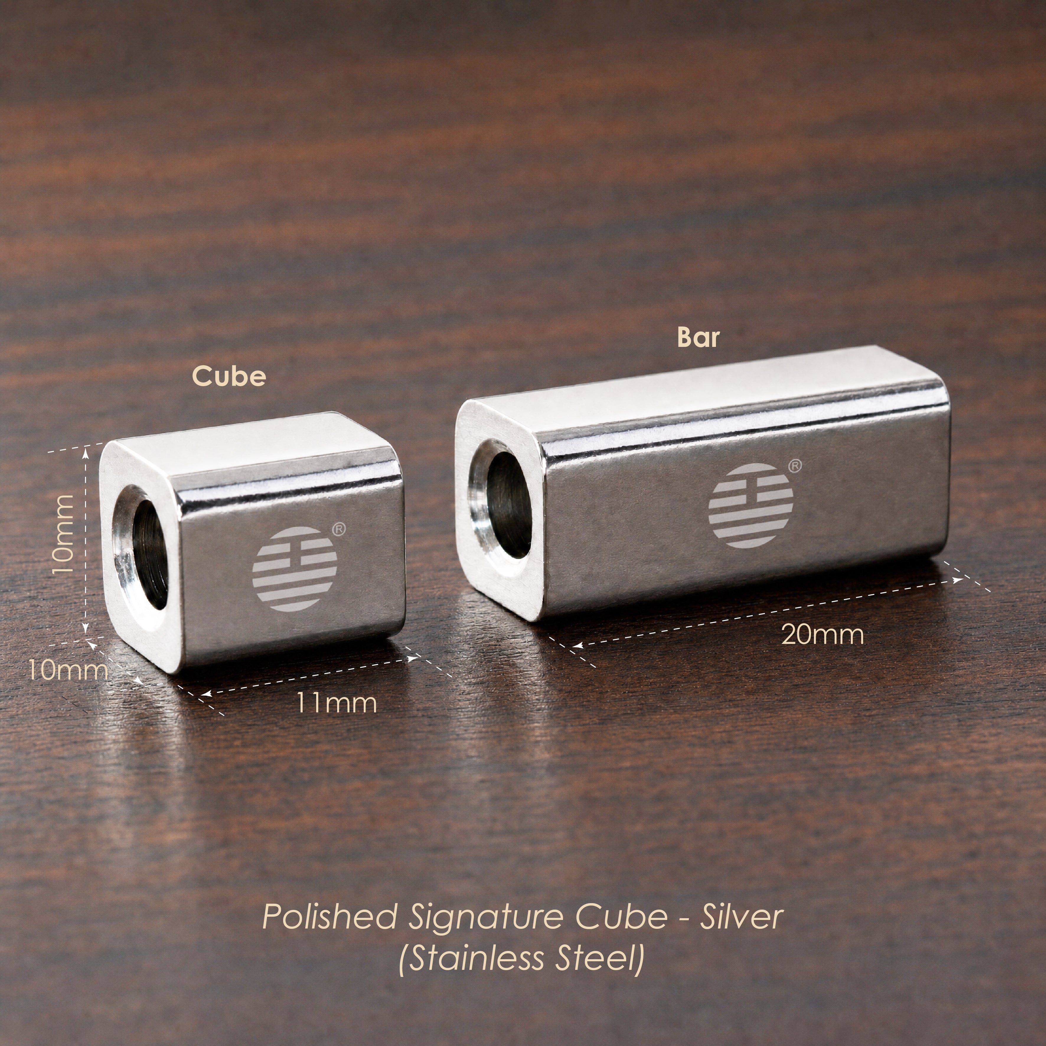 Two silver stainless steel polished signature cubes on a dark wood background, showing dimensions 10mm x 11mm for the smaller cube and 20mm x 10mm for the larger cube, with text reading 'Polished Signature Cube - Silver (Stainless Steel)'.