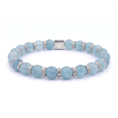 A beaded stretch bracelet made of light blue round gemstone beads and silver-toned spacer beads with a Greek key pattern, featuring a central silver clasp engraved with a heart, shown on a white background.
