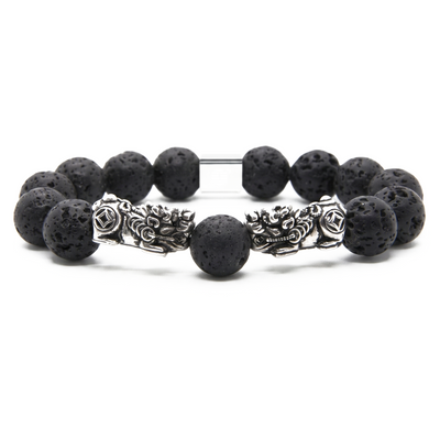 A beaded bracelet featuring matte black porous lava stone beads and two ornate silver-tone metal dragon charms, displayed on a clean white background.