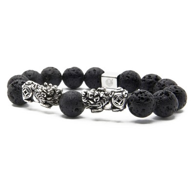 A beaded stretch bracelet featuring matte black lava stone beads and two silver-toned metal dragon charms, displayed on a clean white background.