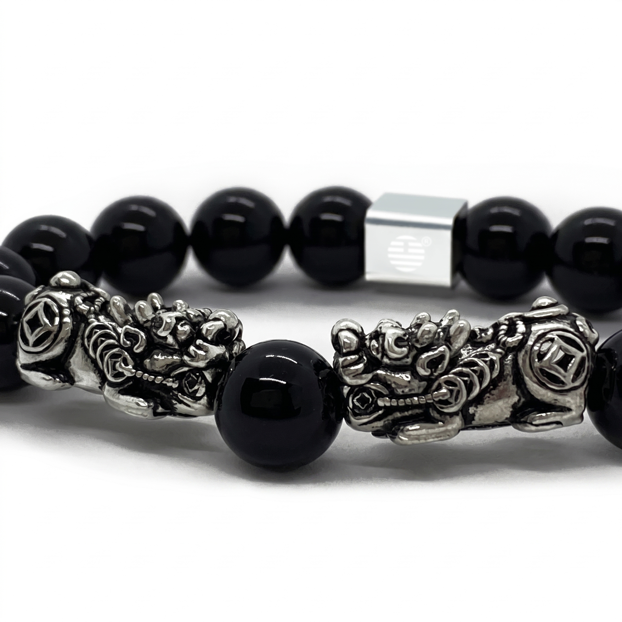 A close-up of a beaded bracelet featuring glossy black round beads, detailed silver-tone dragon charms, and a square silver magnetic clasp on a white background.
