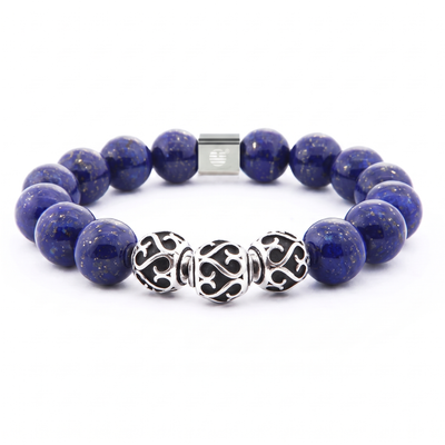 A beaded stretch bracelet featuring deep blue lapis lazuli stones with tiny gold flecks, accented by three ornate silver filigree beads and a silver magnetic clasp, shown on a white background.